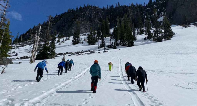 a group of gap year students ascend a snowy incline on an outward bound outdoor educator course